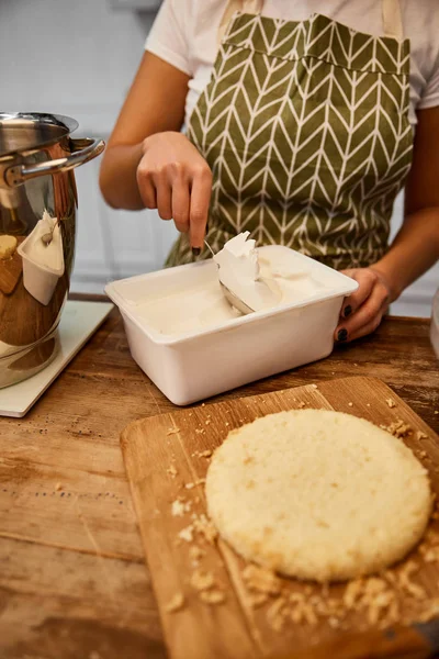 Selektiver Fokus des Konditors, der Sahne zum Kuchenbacken nimmt — Stockfoto