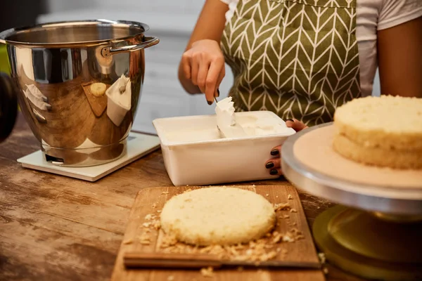 Selective focus of confectioner taking cream for cooking cake in kitchen — Stock Photo