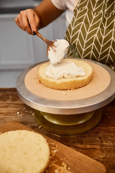 Teilansicht des Konditors, der Sahne auf Kuchenschicht verteilt — Stockfoto