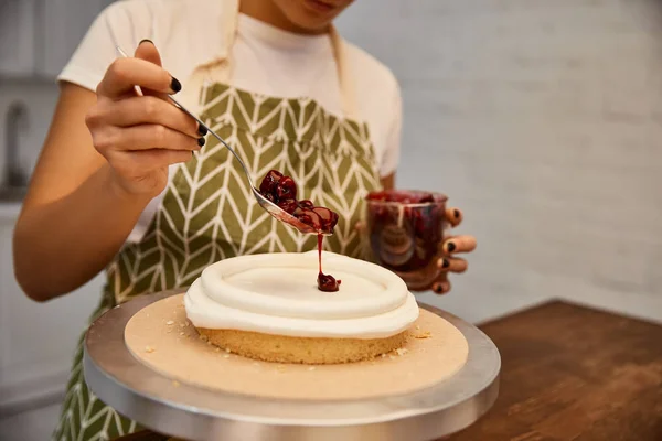 Ausgeschnittene Ansicht von Konditor, der Marmelade auf Kuchen setzt — Stockfoto