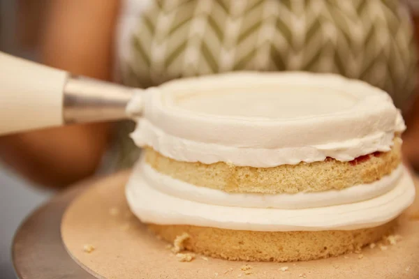 Vista ritagliata del pasticcere che lavora con sacchetto di pasticceria e biscotto — Foto stock