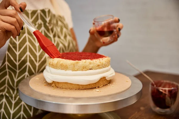 Ausgeschnittene Ansicht eines Konditors, der mit Pinsel und Marmelade auf Keks arbeitet — Stockfoto