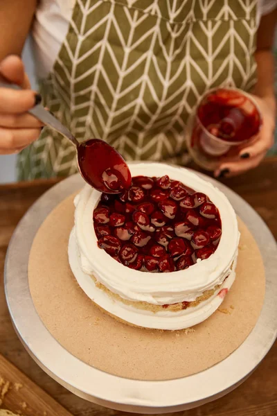 Vista coping de confeiteiro fazendo bolo de esponja com geléia de baga saborosa — Fotografia de Stock