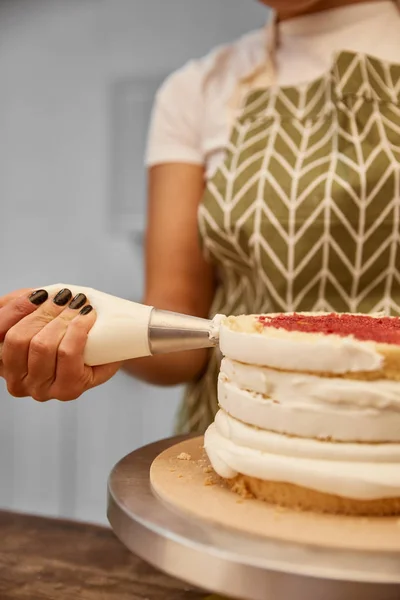 Cropped view of confectioner decorating biscuit with sweet cream — Stock Photo