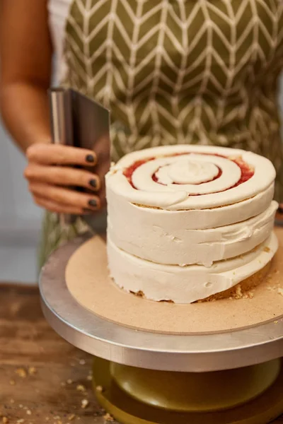 Vista ritagliata del pasticciere che lavora con raschietto e torta — Foto stock