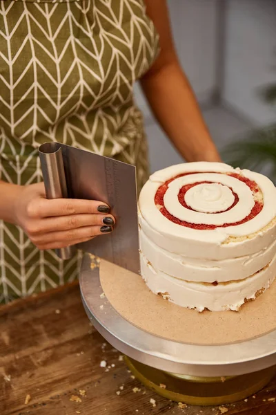 Cropped view of confectioner using smoother while aligning cream on biscuit — Stock Photo