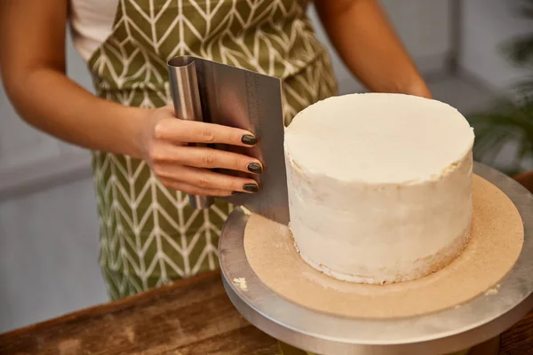 Vista cortada do confeiteiro usando raspador para creme no bolo de esponja — Fotografia de Stock