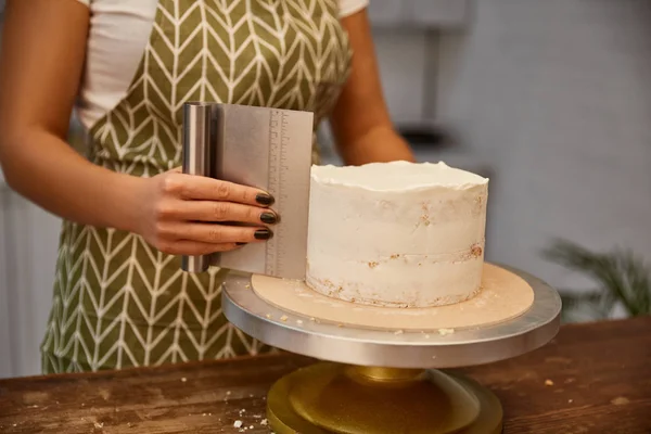 Vue recadrée de confiseur travaillant avec grattoir et gâteau éponge — Photo de stock