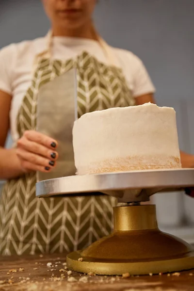 Focus selettivo del pasticcere allineando la crema sulla torta, vista ritagliata — Foto stock