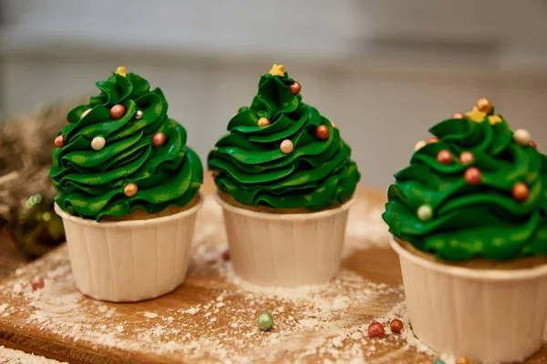 Dekorierte Cupcakes mit grüner Sahne und Zuckerstreusel auf Schneidebrett mit Mehl — Stockfoto