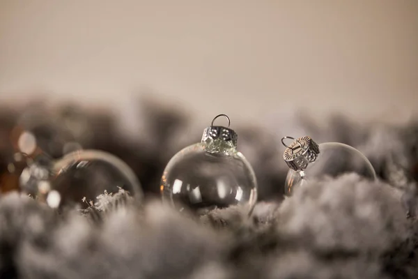 Transparent christmas balls on spruce branches in snow — Stock Photo