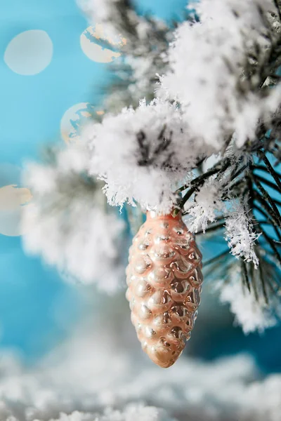 Gros plan de branches d'épinette dans la neige avec cône de sapin boule de Noël sur bleu — Photo de stock