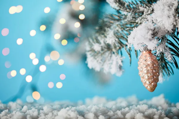 Fichtenzweige im Schnee mit Weihnachtskugel Tannenzapfen und Lichtern Bokeh auf blau — Stockfoto