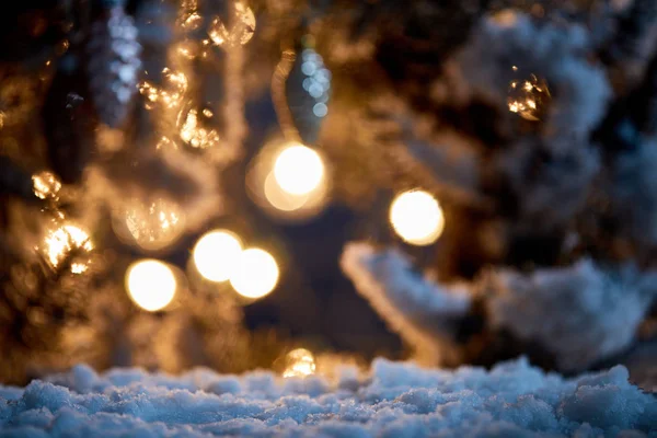 Gros plan des branches d'épinette dans la neige avec des boules de Noël et des lumières bokeh la nuit — Photo de stock