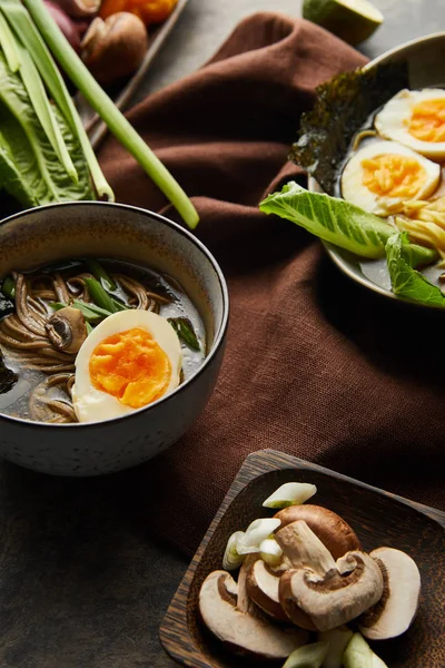 Ramen picante tradicional em tigelas em guardanapo marrom na superfície de pedra — Fotografia de Stock