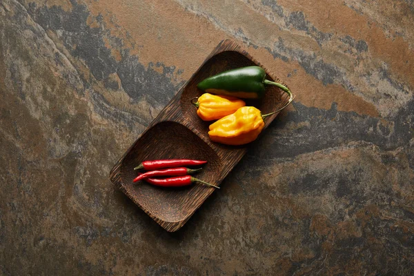 Top view of fresh peppers on wooden board on stone surface — Stock Photo
