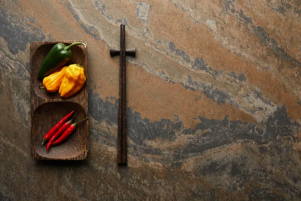 Top view of chopsticks and fresh peppers on stone surface — Stock Photo