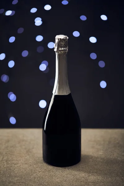 Bottle of sparkling wine with blurred christmas lights — Stock Photo