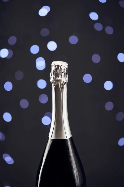 Close up of sparkling wine bottle with blue christmas lights bokeh — Stock Photo
