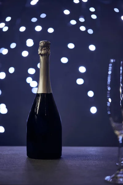 Selektiver Fokus von Champagnerflasche und Glas mit Weihnachtsbeleuchtung Bokeh — Stockfoto