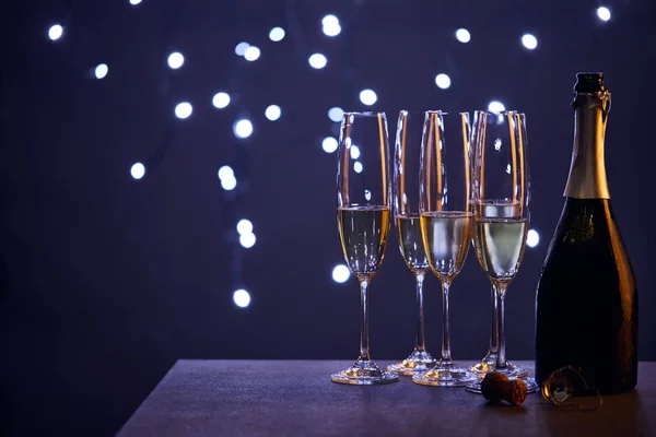 Champagne in bottle and glasses with blue christmas lights bokeh — Stock Photo