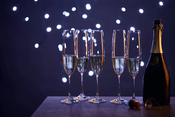 Espumante de vinho em garrafa e copos com luzes de Natal azul bokeh — Fotografia de Stock