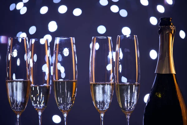 Ігристе вино в пляшці і окулярах з розмитими синіми різдвяними вогнями — стокове фото