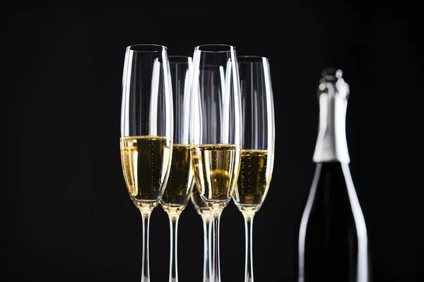 Склянки і пляшка шампанського для святкування Різдва, ізольовані на чорному — стокове фото