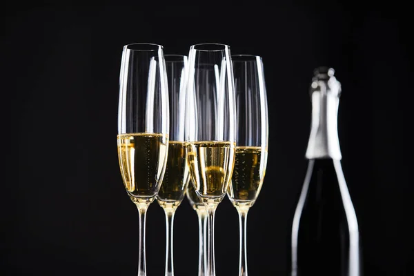 Verres et bouteille de champagne pour célébrer Noël, isolé sur noir — Photo de stock