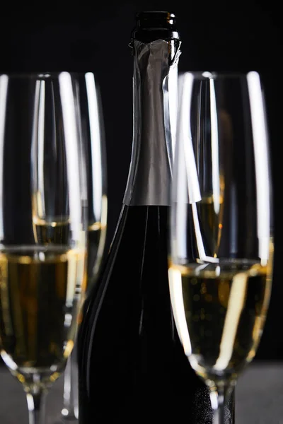 Glasses and bottle of sparkling wine on black — Stock Photo