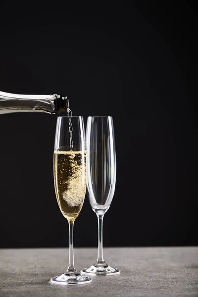 Gros plan de champagne verser de la bouteille dans des verres pour célébrer Noël sur noir — Photo de stock