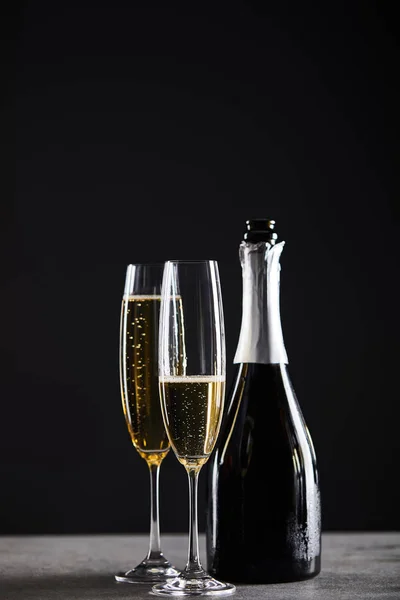 Copos e garrafa de vinho espumante para celebrar o Natal em preto — Fotografia de Stock