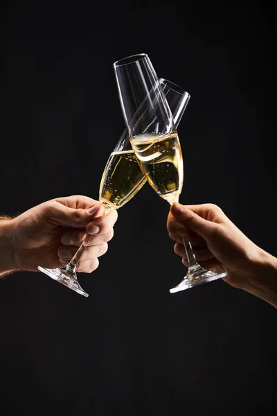 Cropped view of man and woman clinking with champagne glasses and celebrating christmas, isolated on black — Stock Photo