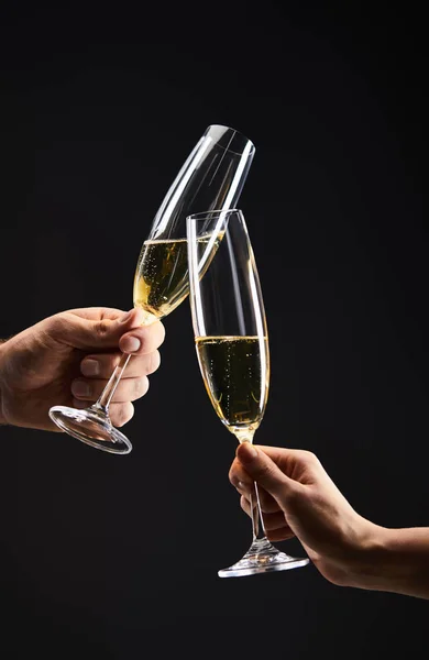 Vue recadrée du couple cliquetant avec des verres à champagne et célébrant la veille de Noël, isolé sur noir — Photo de stock