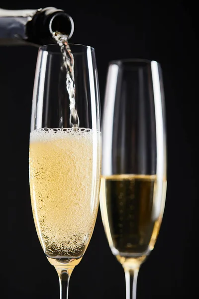 Nahaufnahme von Champagner, der zur Weihnachtsfeier in Gläser gegossen wird, isoliert auf schwarz — Stockfoto