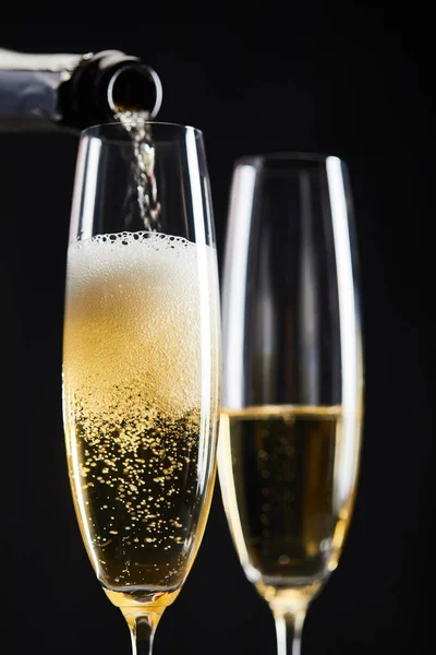 Sparkling wine pouring from bottle into glasses for celebrating christmas, isolated on black — Stock Photo