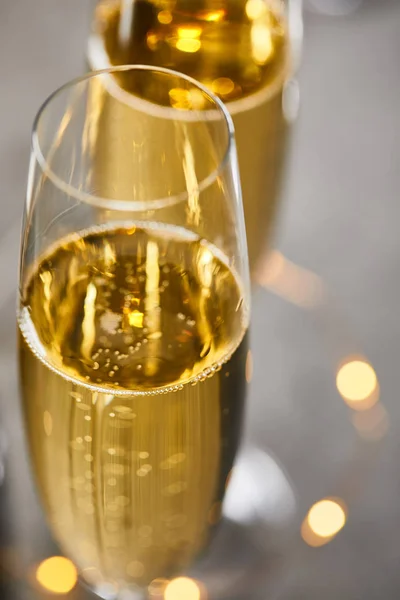 Primer plano de copas de champán con luces de Navidad amarillas borrosas - foto de stock