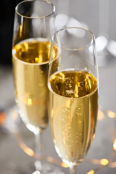 Close up of glasses of sparkling wine with blurred yellow christmas lights — Stock Photo