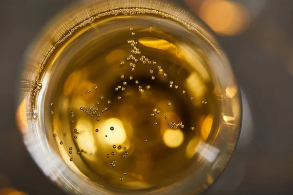 Vue du dessus du vin mousseux en verre avec des lumières de Noël jaunes floues — Photo de stock