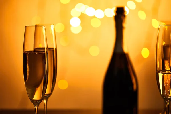 Bicchieri e bottiglia di champagne con luci di Natale gialle bokeh — Foto stock