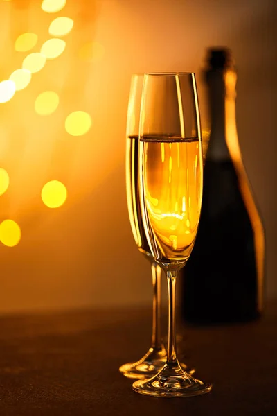 Glasses of champagne with blurred bottle and yellow christmas lights — Stock Photo