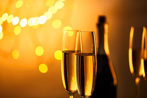 Copos de vinho espumante com garrafa borrada e luzes de Natal amarelas — Fotografia de Stock