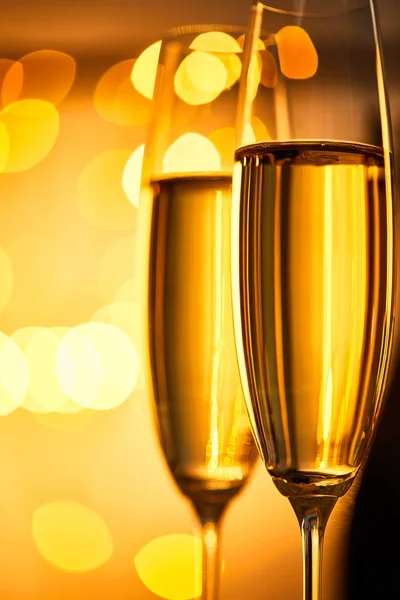 Close up of glasses of champagne with yellow christmas lights bokeh — Stock Photo