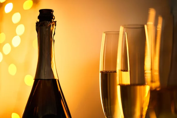 Gläser und Flasche Champagner mit gelben Weihnachtslichtern Bokeh — Stockfoto