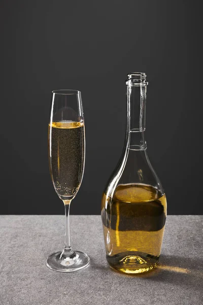 Copa y botella de vino espumoso para celebrar la víspera de Navidad en gris - foto de stock