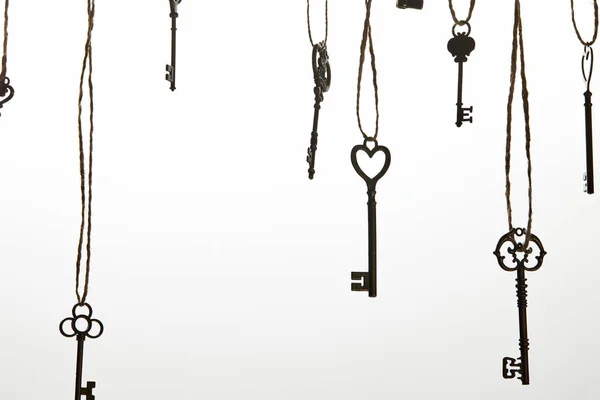 Vintage keys hanging on ropes isolated on white — Stock Photo