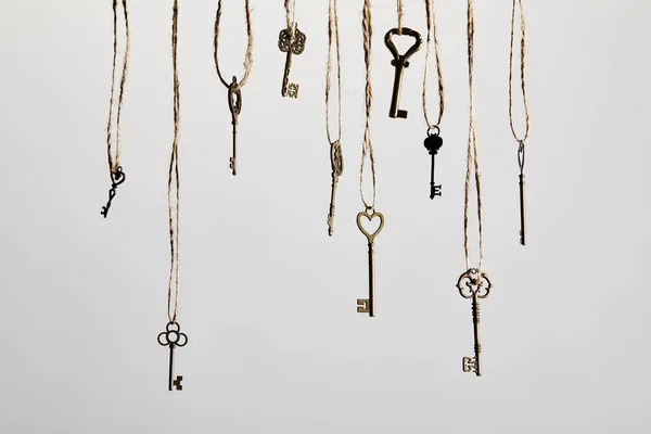 Vintage keys hanging on ropes isolated on white — Stock Photo