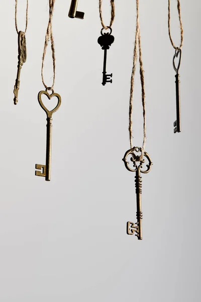 Vintage keys hanging on ropes isolated on white — Stock Photo