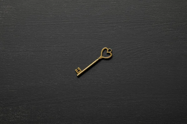 Vista dall'alto di chiave arrugginita vintage con cuore su sfondo nero — Foto stock