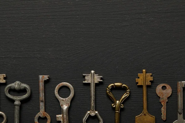 Flat lay with vintage rusty keys on black background — Stock Photo